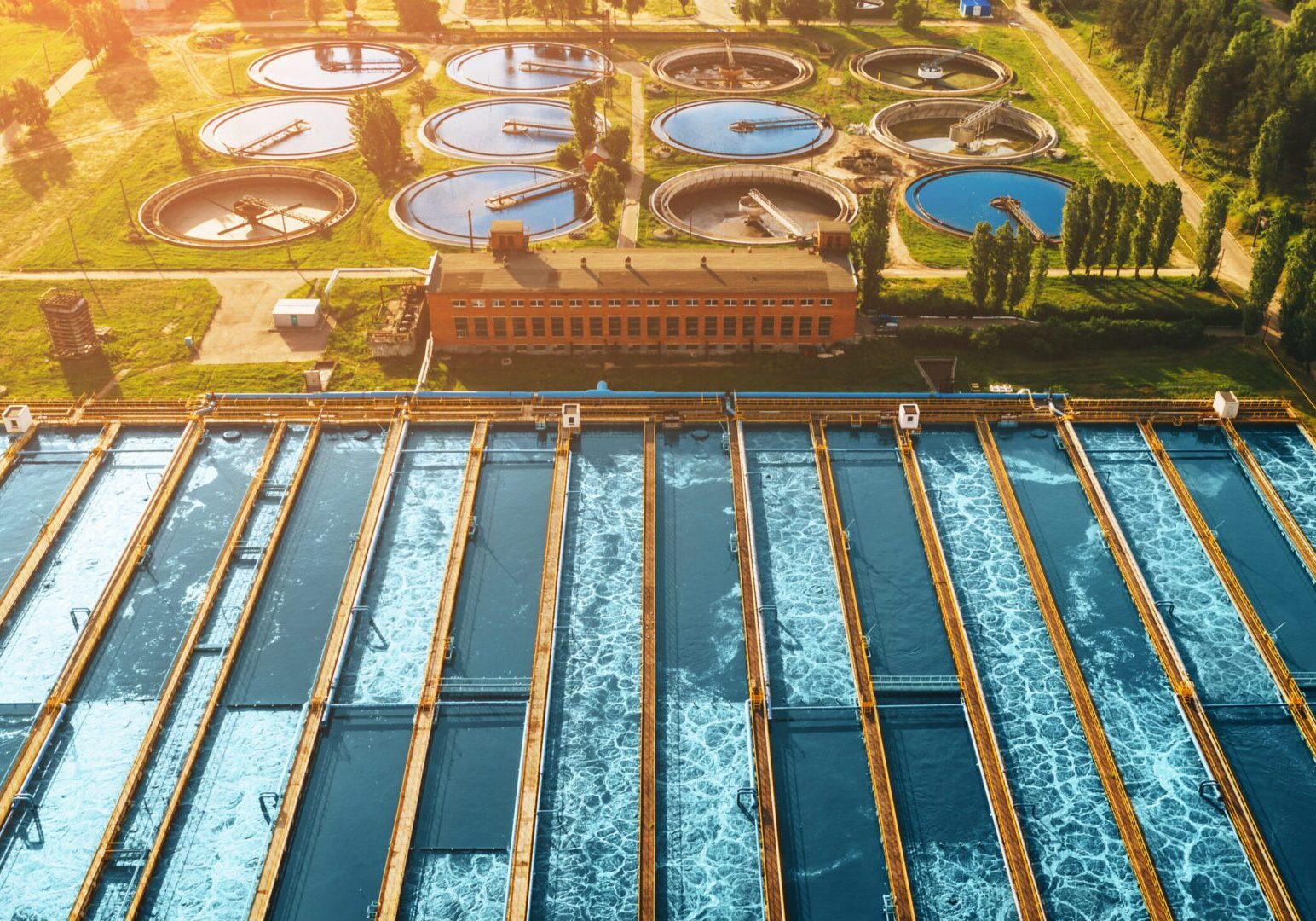 Modern industrial sewage treatment plant at sunset, aerial view from drone.